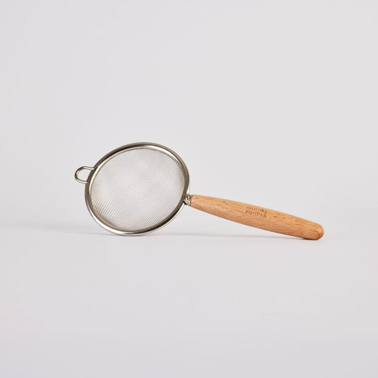 Metal matcha sieve with a bamboo handle, perfect for preparing ceremonial grade matcha