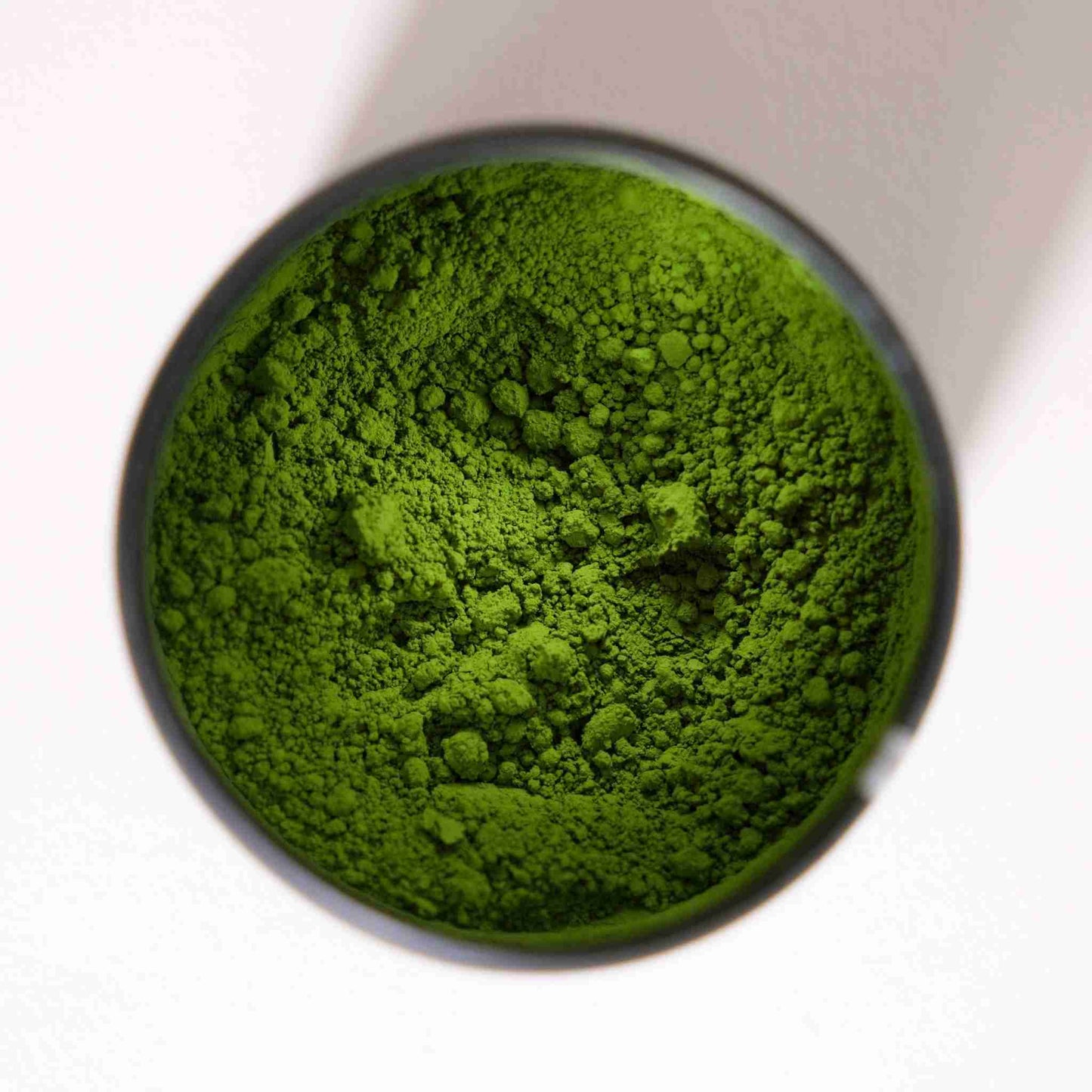 Close-up of Good & Proper Tea Signature Matcha green tea powder in a small container on a white background