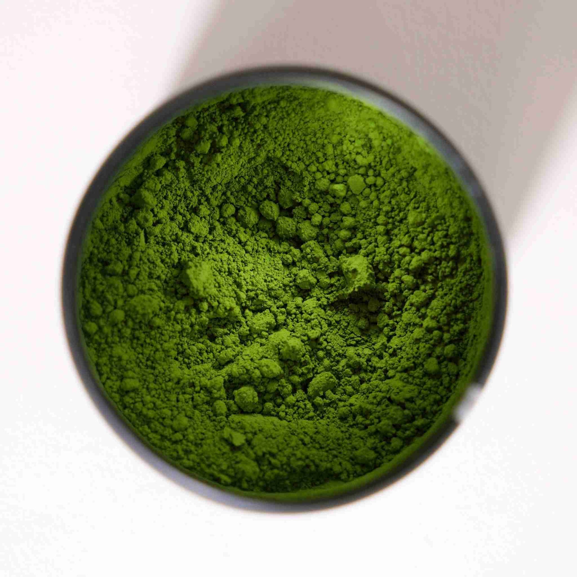 Close-up of Good & Proper Tea Signature Matcha green tea powder in a small container on a white background